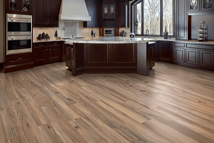 Tampa Flooring | How to Care for Granite Countertops and Keep Them Looking New A spacious kitchen featuring rich cherry wood cabinets, light-colored hardwood floors, and a large island with a lighter-toned countertop.