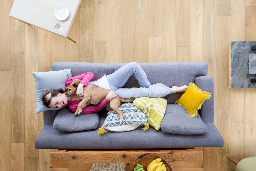 Tampa Flooring | How Long Does It Really Take to Install New Flooring in Tampa? A woman and a dog lying on a couch placed on a hardwood floor.