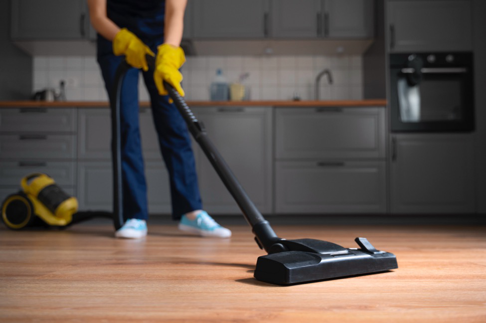 A vacuum cleaner on a wood floor cleaning up debris and dust.