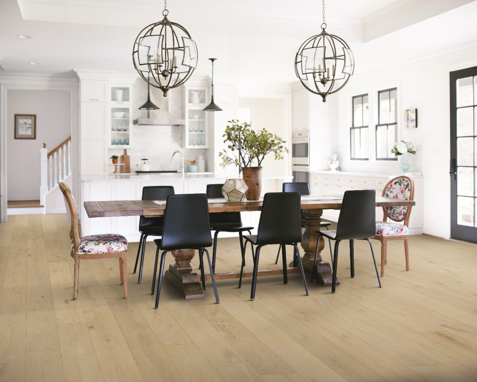 A dining room table sits in an open kitchen with vinyl flooring that looks like wood. 