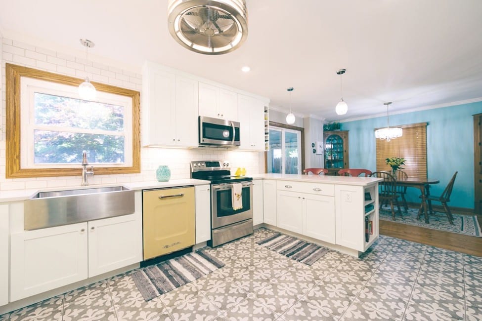 A modern kitchen featuring durable porcelain tile flooring and white Wellborn cabinets.[