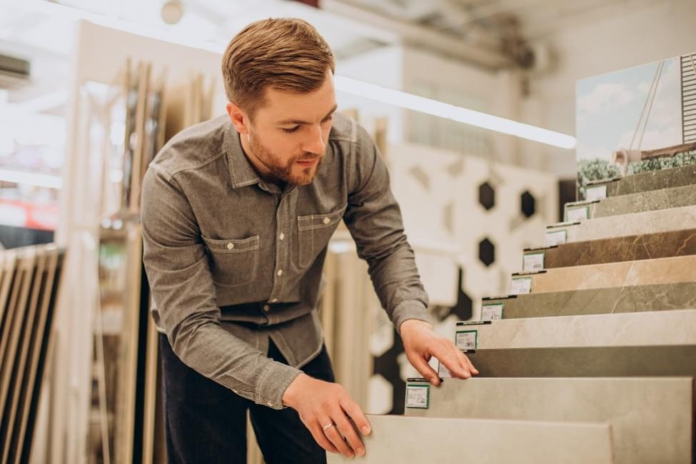 Homeowner comparing tile sizes at a flooring showroom.